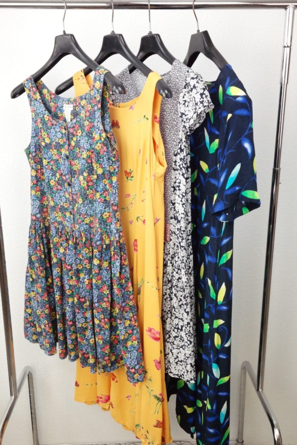 Unterschiedlich lange Vintage Blümchenkleider hängen auf Bügeln auf einem Kleiderständer.